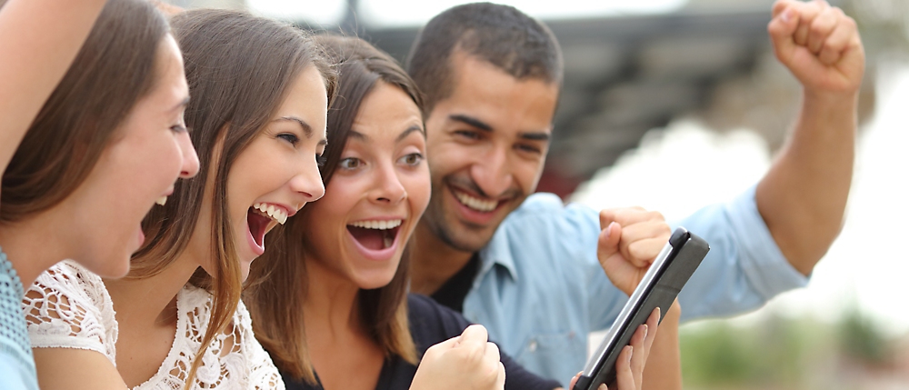 A group of people laughing and looking at a tablet