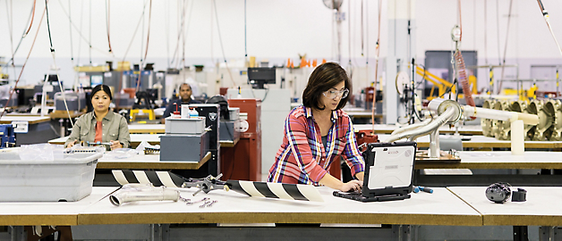 Two individuals working with aerospace components in an industrial manufacturing facility.