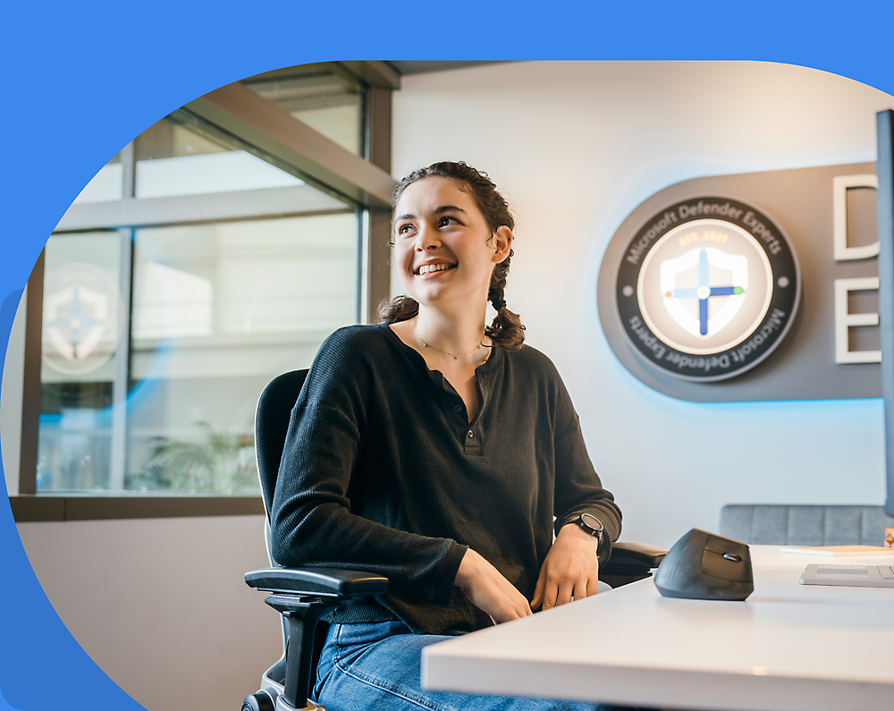 A person smiling, sitting at a desk