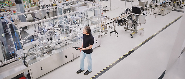 A person stands observing an automated production line in a clean and modern manufacturing facility.