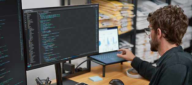 Softwareudvikler, der arbejder på kode på en arbejdsstation med to skærme.