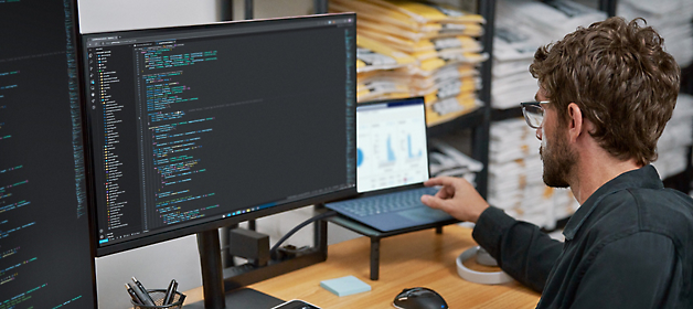 Un desarrollador de software trabaja con código en una estación de trabajo de dos monitores.