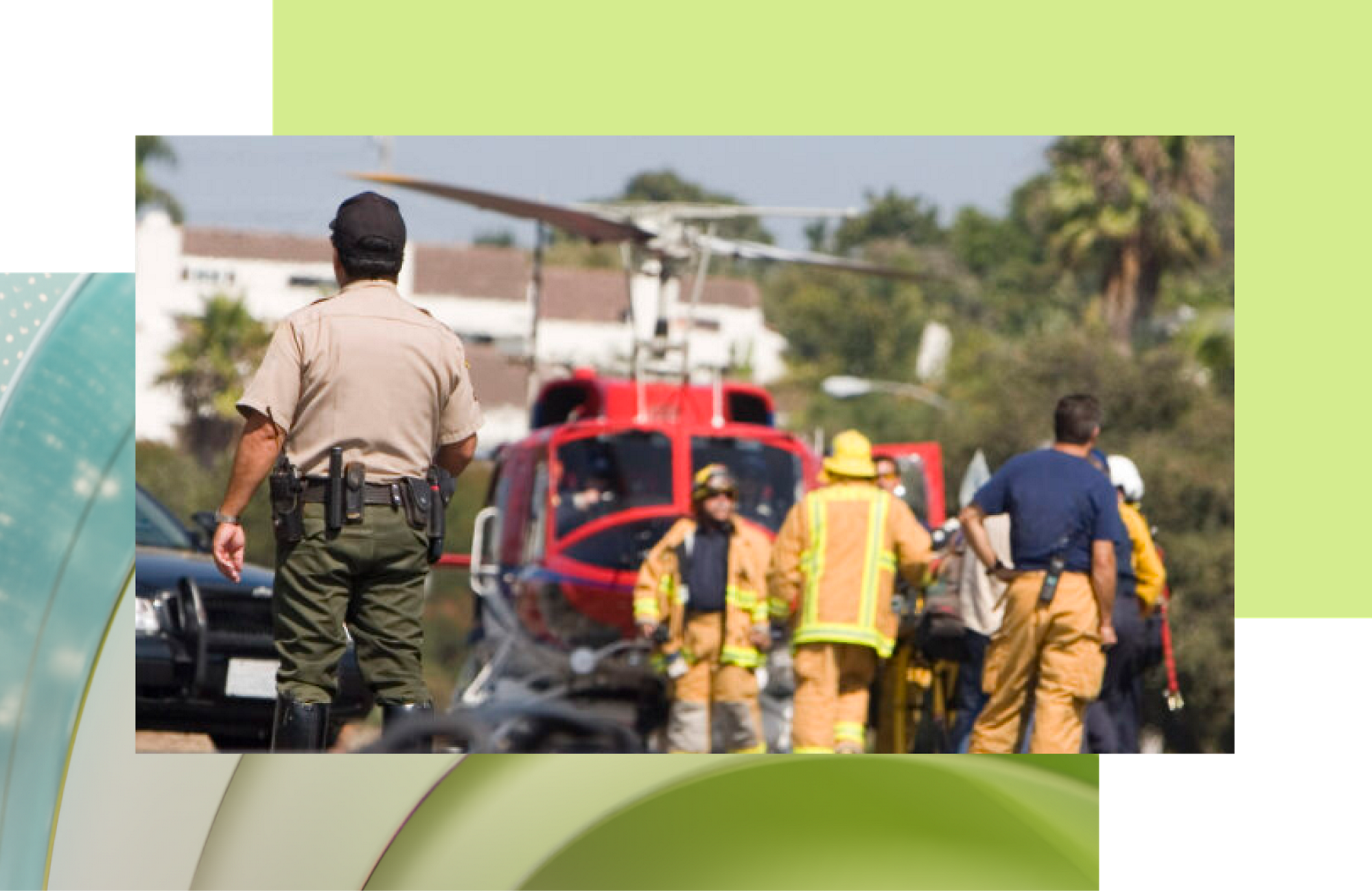 A police officer observes firefighters near a red helicopter at an emergency scene.