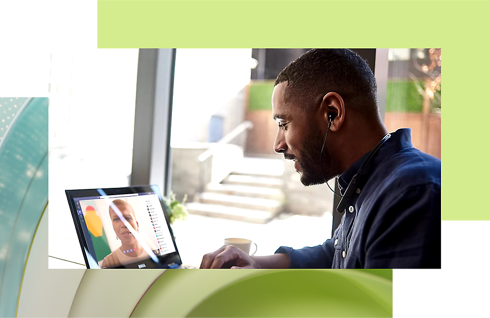 A man wearing earphones uses a laptop in a modern office setting, engaged in a video call with a woman 