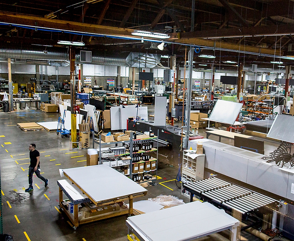 A person walking through a busy manufacturing workshop with various stations and materials.