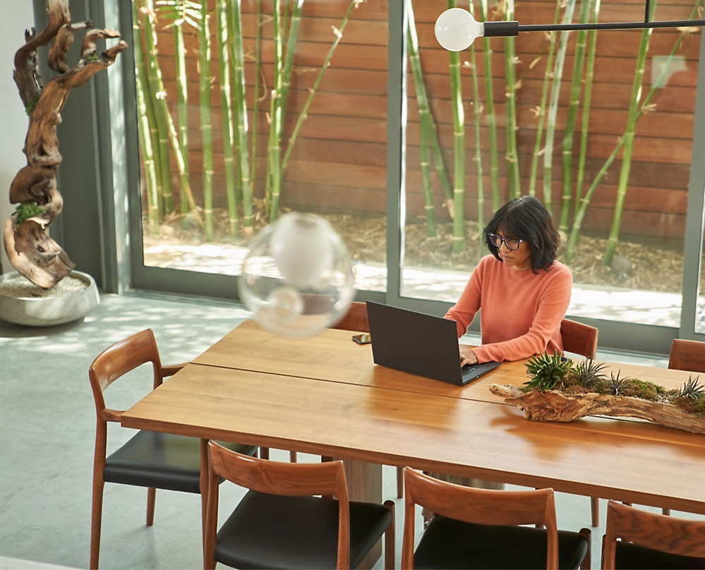 Egy asztalnál ülő, laptopot használó személy