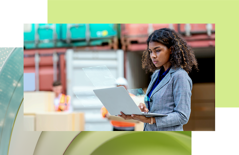 A woman using a laptop in a shipping yard, with workers and cargo containers in the background.