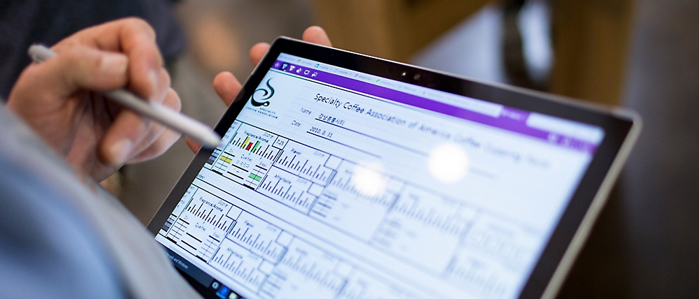 En person som bruker en pekepenn på et nettbrett for å vise diagrammer og analyser på et finansielt instrumentbord.