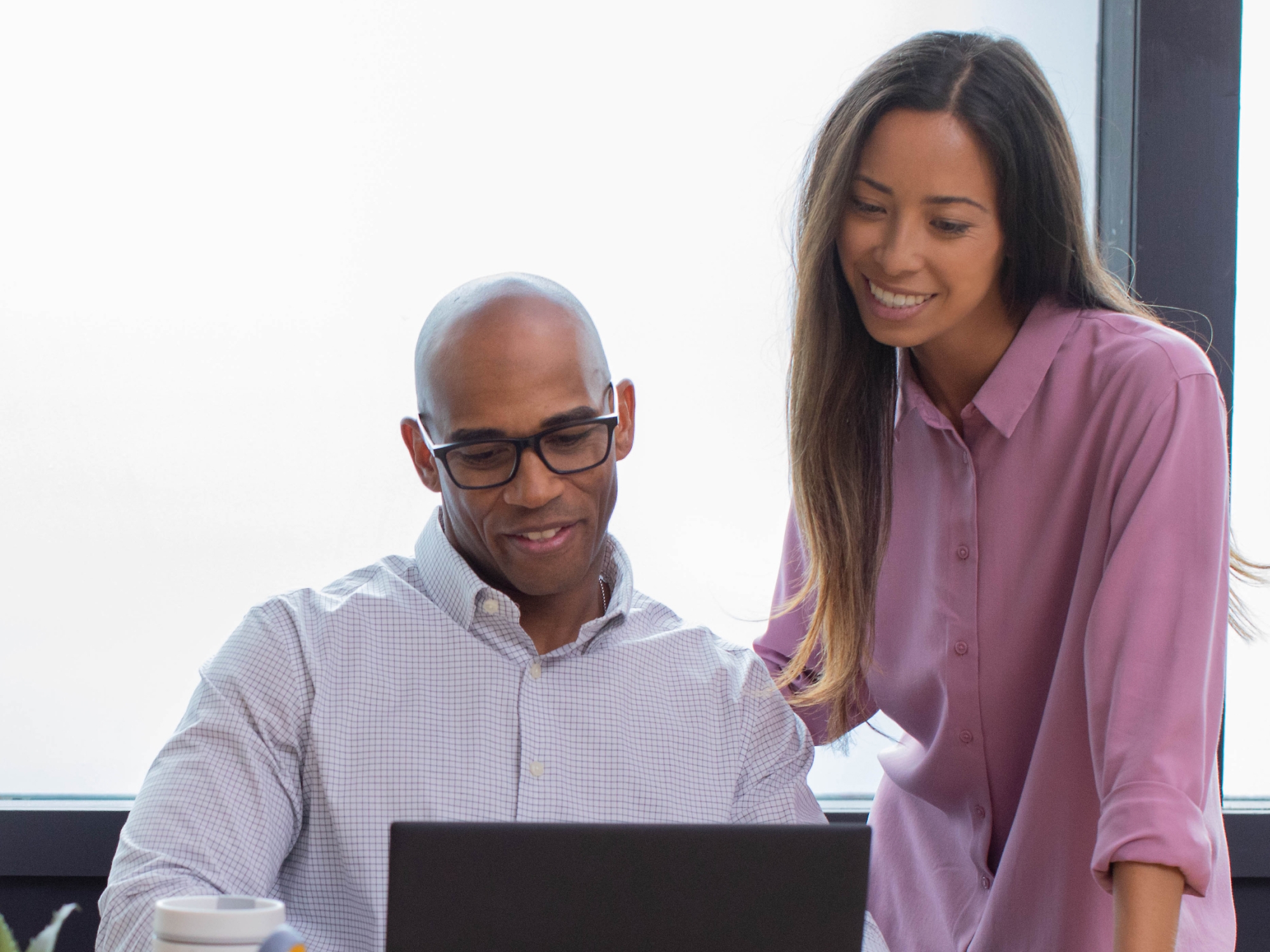 A person and another person looking at a computer