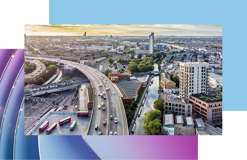 Vista aérea de una concurrida autopista de ciudad con varios carriles y autobuses rojos, rodeado de edificios modernos.