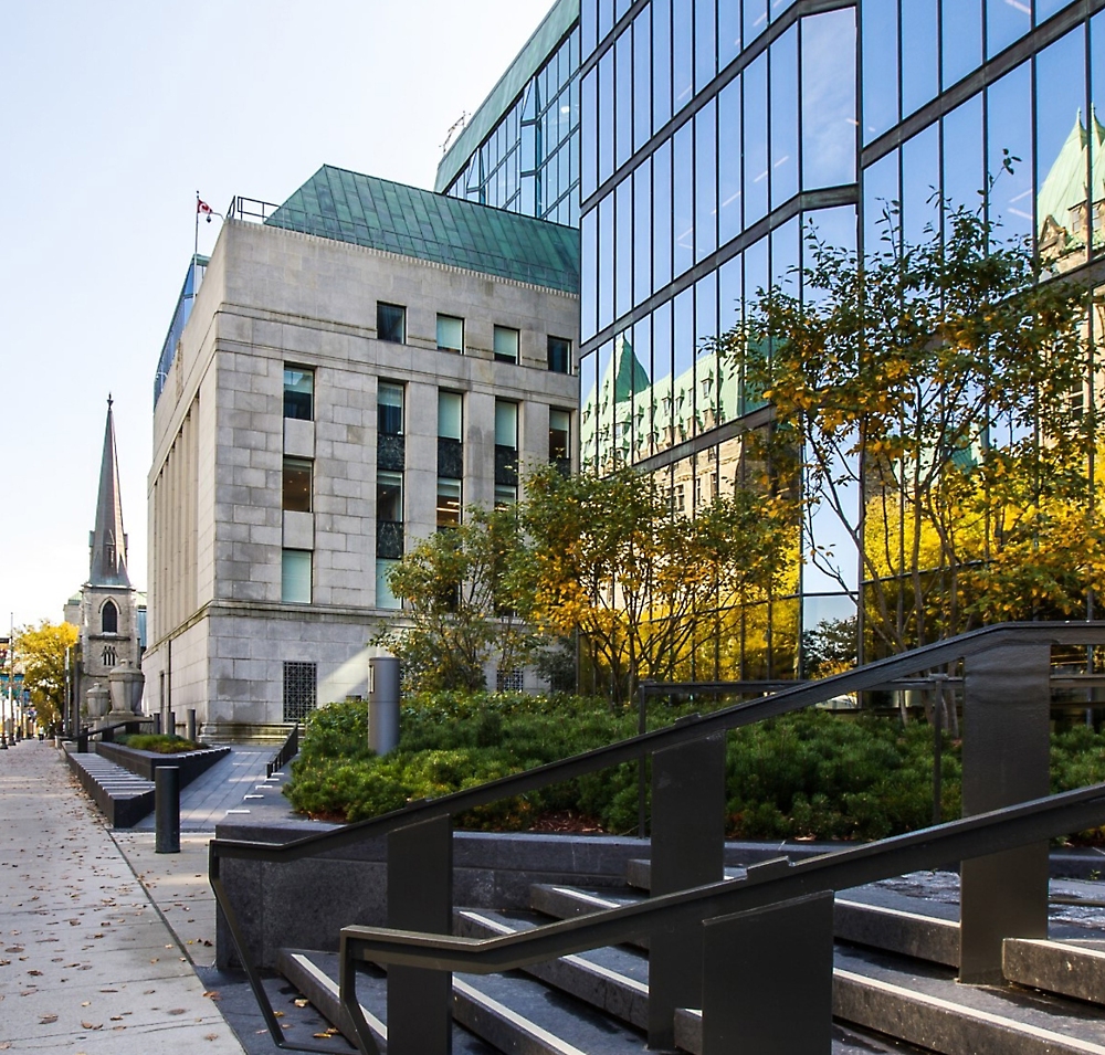 Modern urban landscape featuring a glass and stone building with a historic church visible in the background