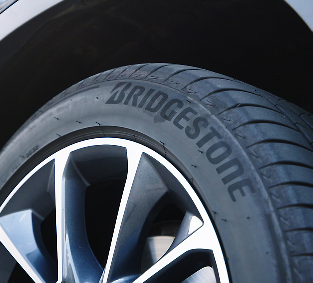 Nahaufnahme eines Bridgestone-Reifens auf einem Leichtmetallrad eines Autos.