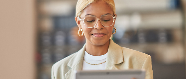 A woman wearing glasses and a tan jacket.