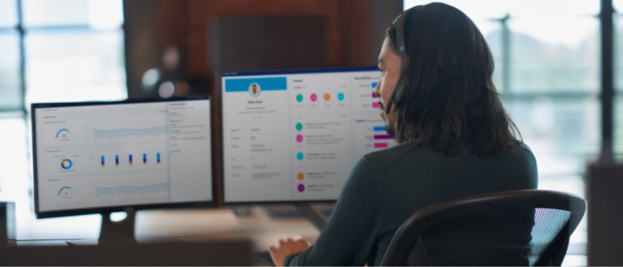 A man is sitting in front of computer screens and working