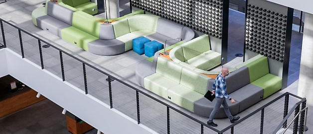 Ein Mann geht an modernen, farbenfrohen Sitzgelegenheiten in einer geräumigen Lobby mit einem Balkongeländer vorbei.