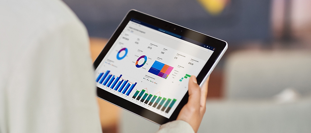 A person holding a tablet displaying various charts and graphs