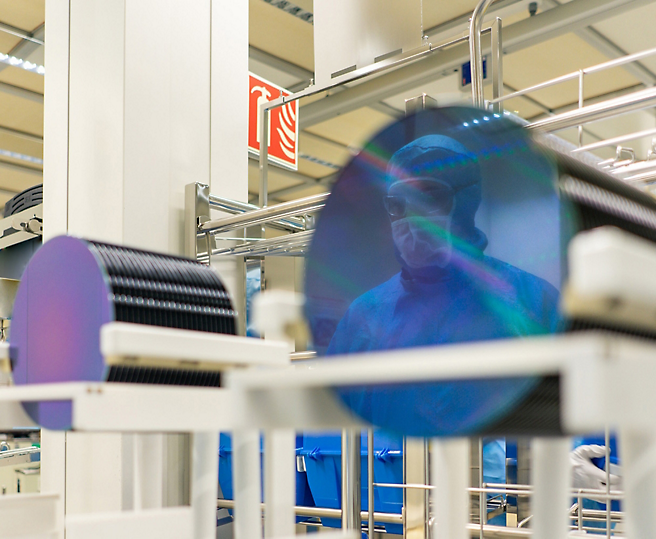 Un técnico con el atuendo correspondiente inspecciona la producción de semiconductos en una instalación de alta tecnología.