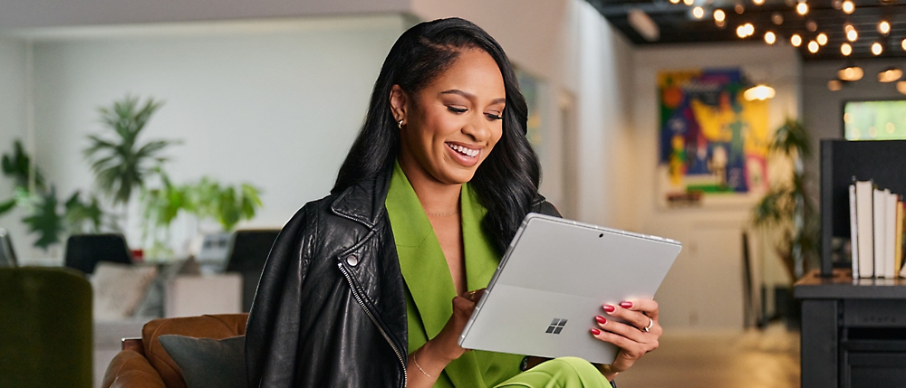 A person in green and black jacket holding a tablet