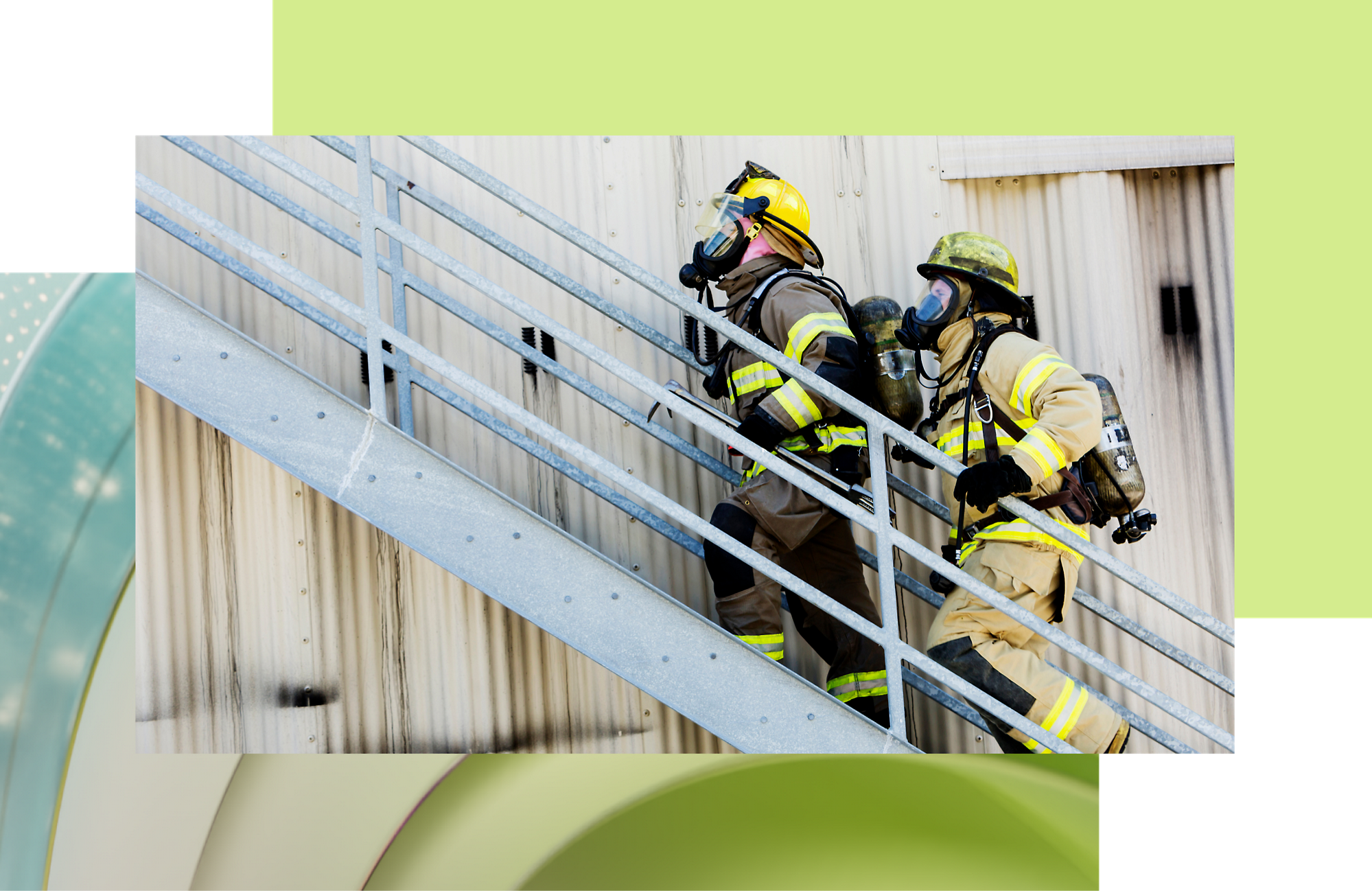 Zwei Feuerwehrmänner in voller Montur steigen während einer Notfallübung eine Metalltreppe im Freien hinauf.