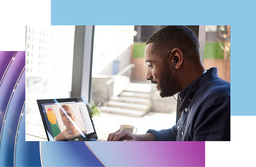 A man works on his laptop by a window overlooking the city.