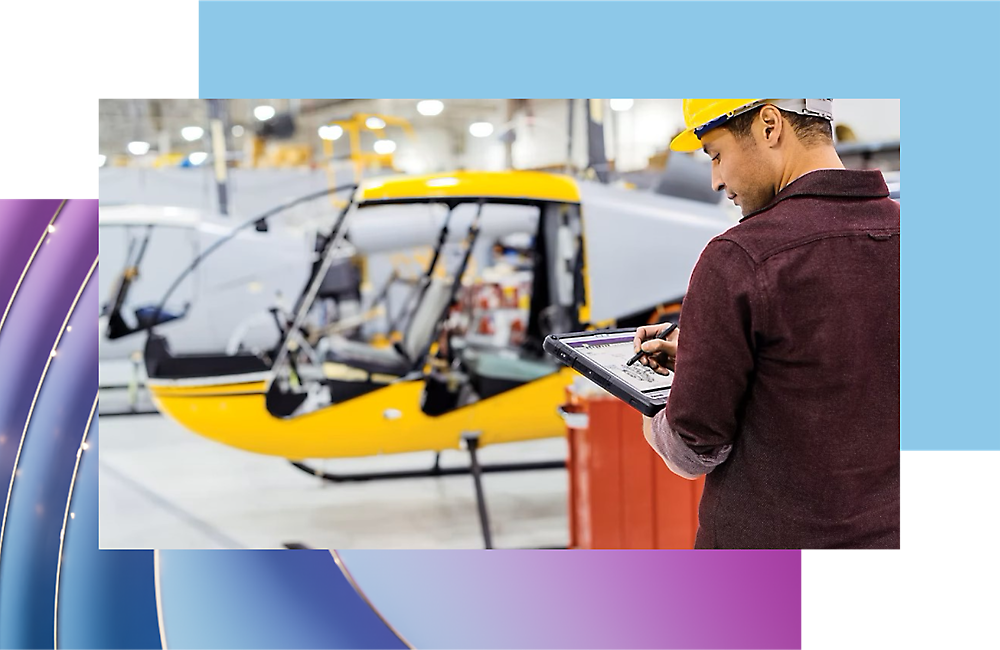 Arbejder undersøger flyproduktionsstatus med en digital tablet i en hangar.