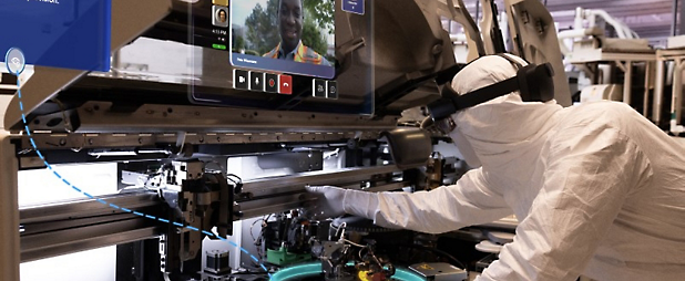 Un técnico con atuendo de sala blanca opera un equipo de fabricación avanzado en una instalación de alta tecnología.