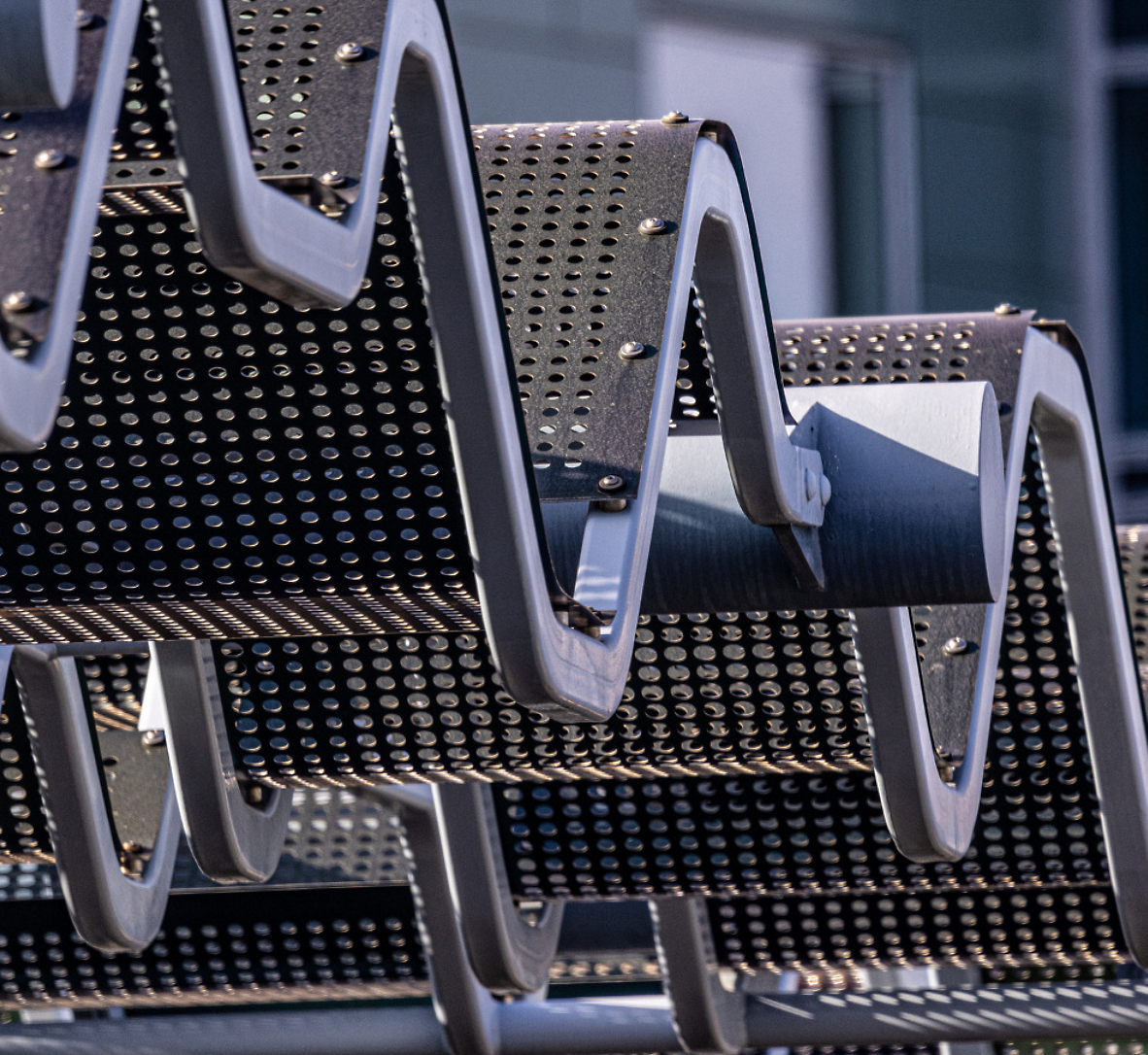 Close-up of a zigzagging metallic structure with perforated surface