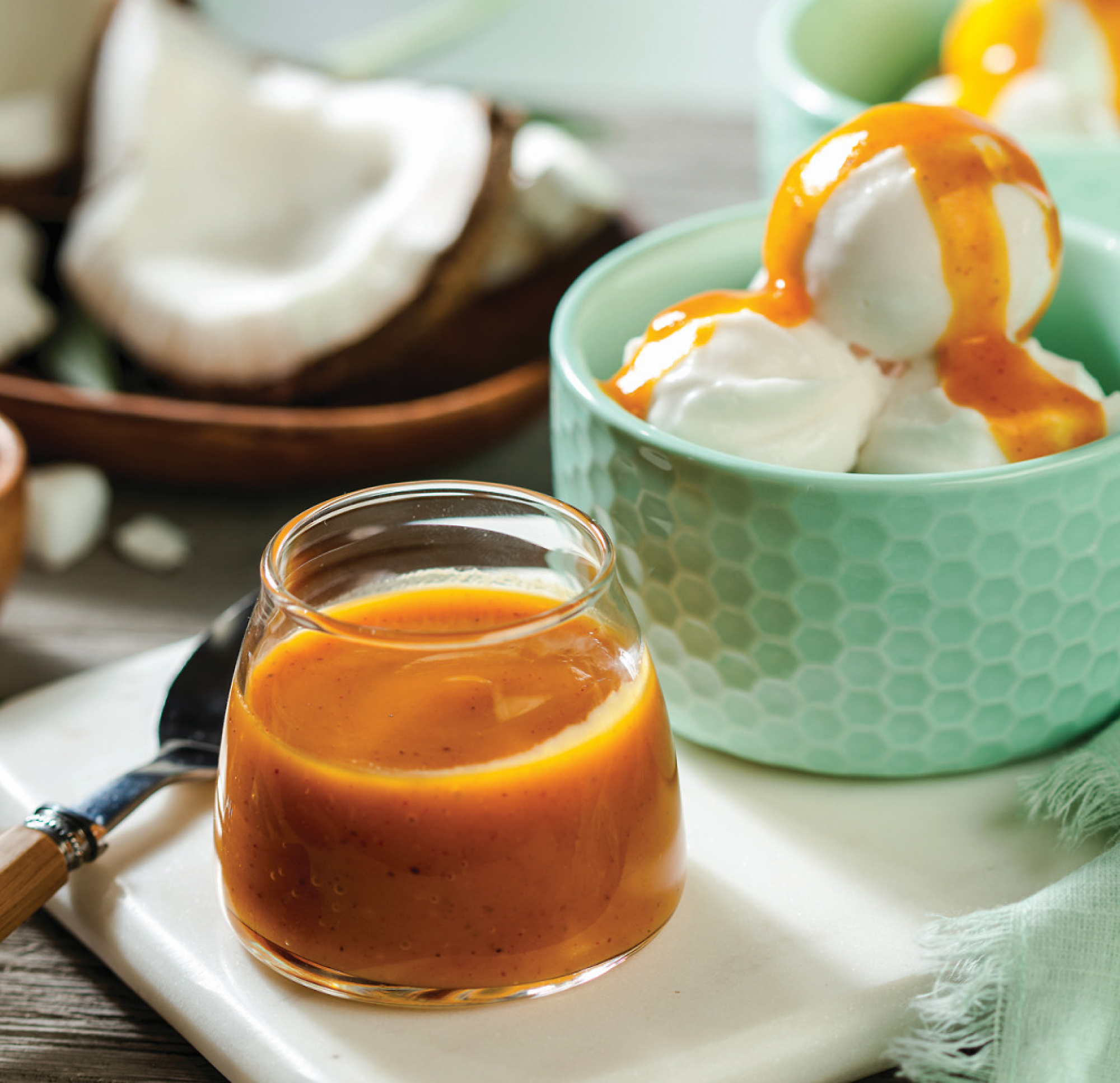 A cup of tea sits on a white tray next to a bowl of vanilla ice cream topped with the caramel sauce.