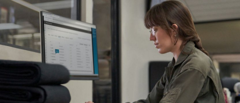 Uma mulher sentada em uma mesa usando um computador