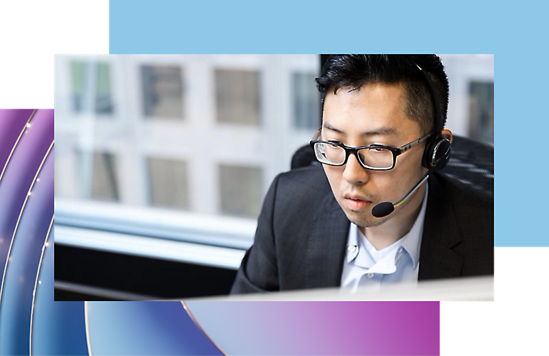 Man in glasses and headset focusing on a computer screen in an office setting.