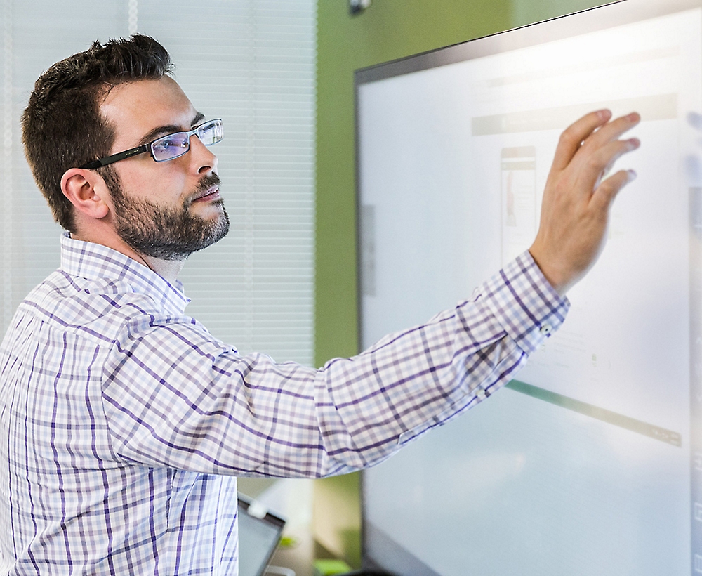 A person is wearning glasses and touching a screen