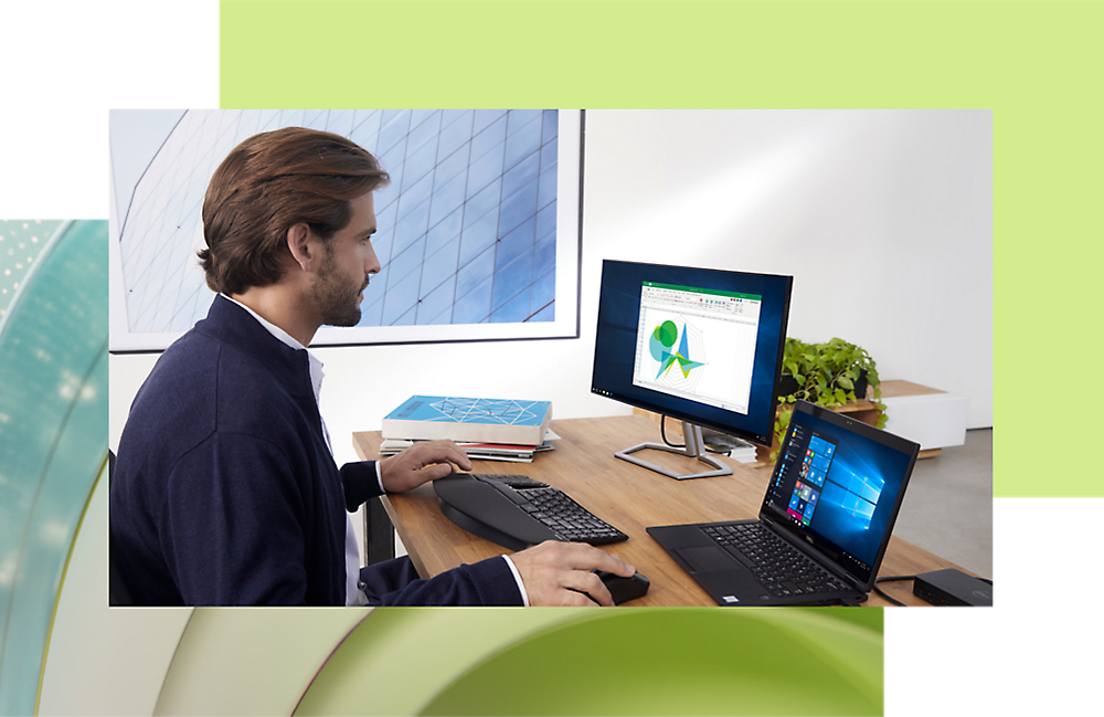 صورة لرجل يعمل على كمبيوتر مكتبي وكمبيوتر محمول في مكتب حديث، ويحلل البيانات على الشاشة باستخدام المخططات الرسومية.