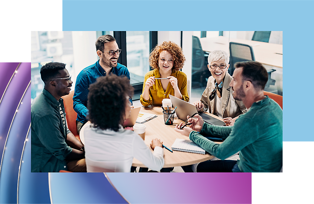 Een diverse groep van zes professionals die een gesprek voeren rond een tafel met laptops en notebooks in een kantooromgeving.