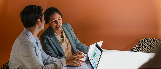 Two professionals collaborating over a laptop in an office setting.