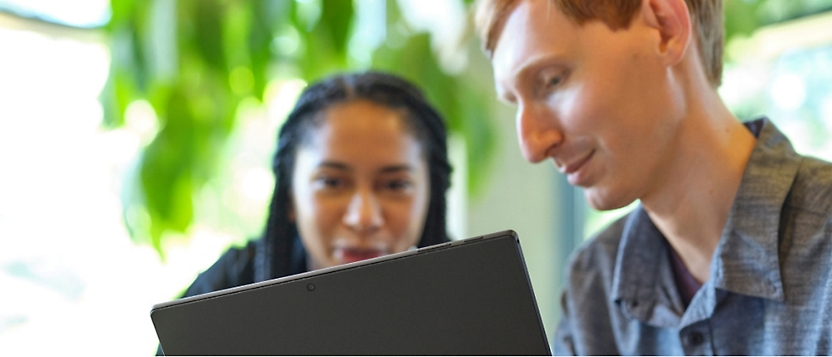 A person and another person looking at a computer.