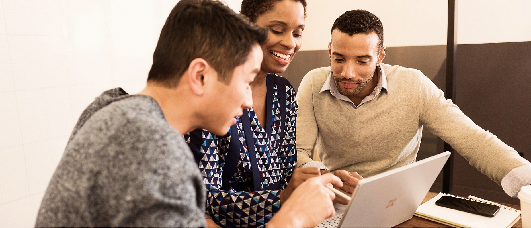 Three people discussing something with a laptop in smiling face