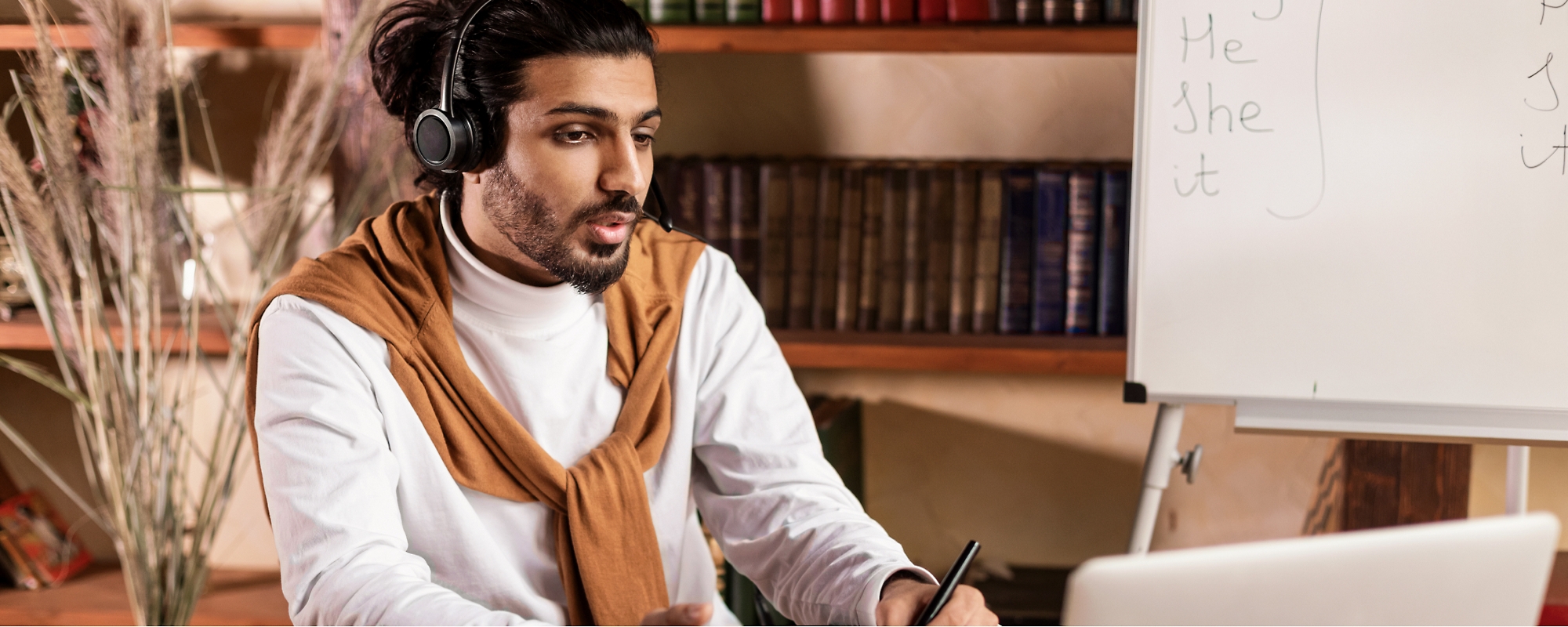 A man wearing headset and working with laptop