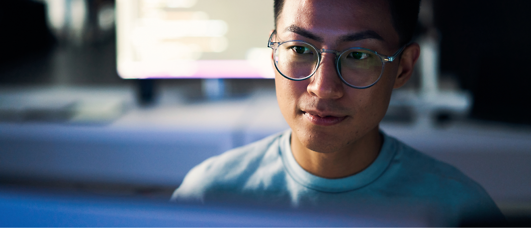 A person wearing glasses working on his computer