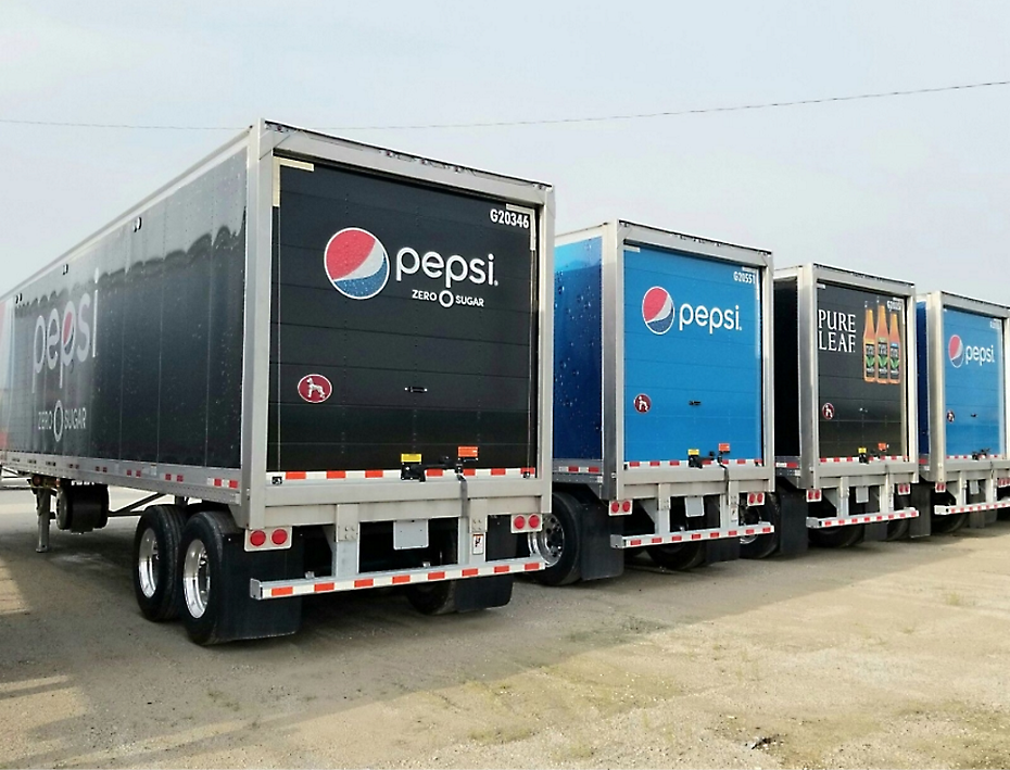 Four delivery trucks are parked in a row, displaying branding for Pepsi, Pepsi Zero Sugar, and Pure Leaf iced tea.