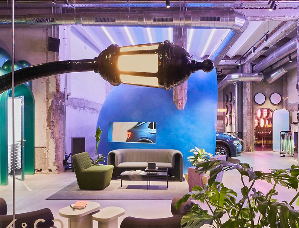 A modern indoor space with a unique, curved streetlamp fixture, contemporary furniture, plants, and a blue wall