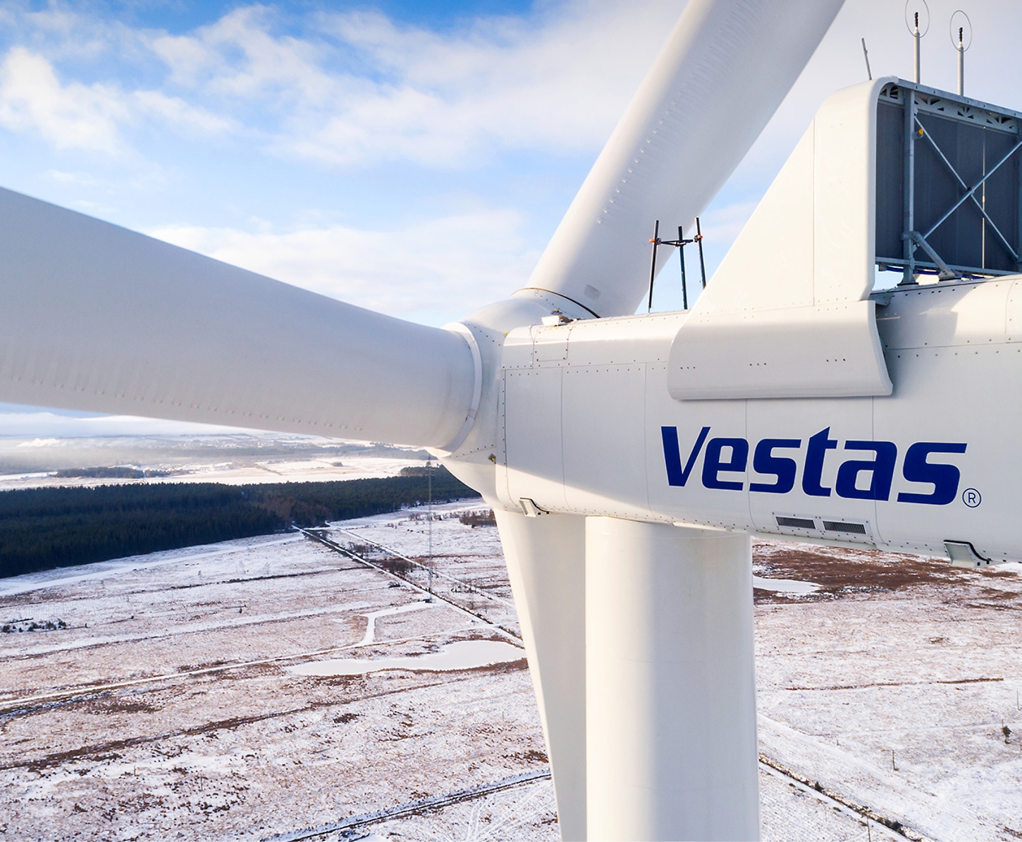 Close-up of a Vestas wind turbine with snow-covered landscape in the background.