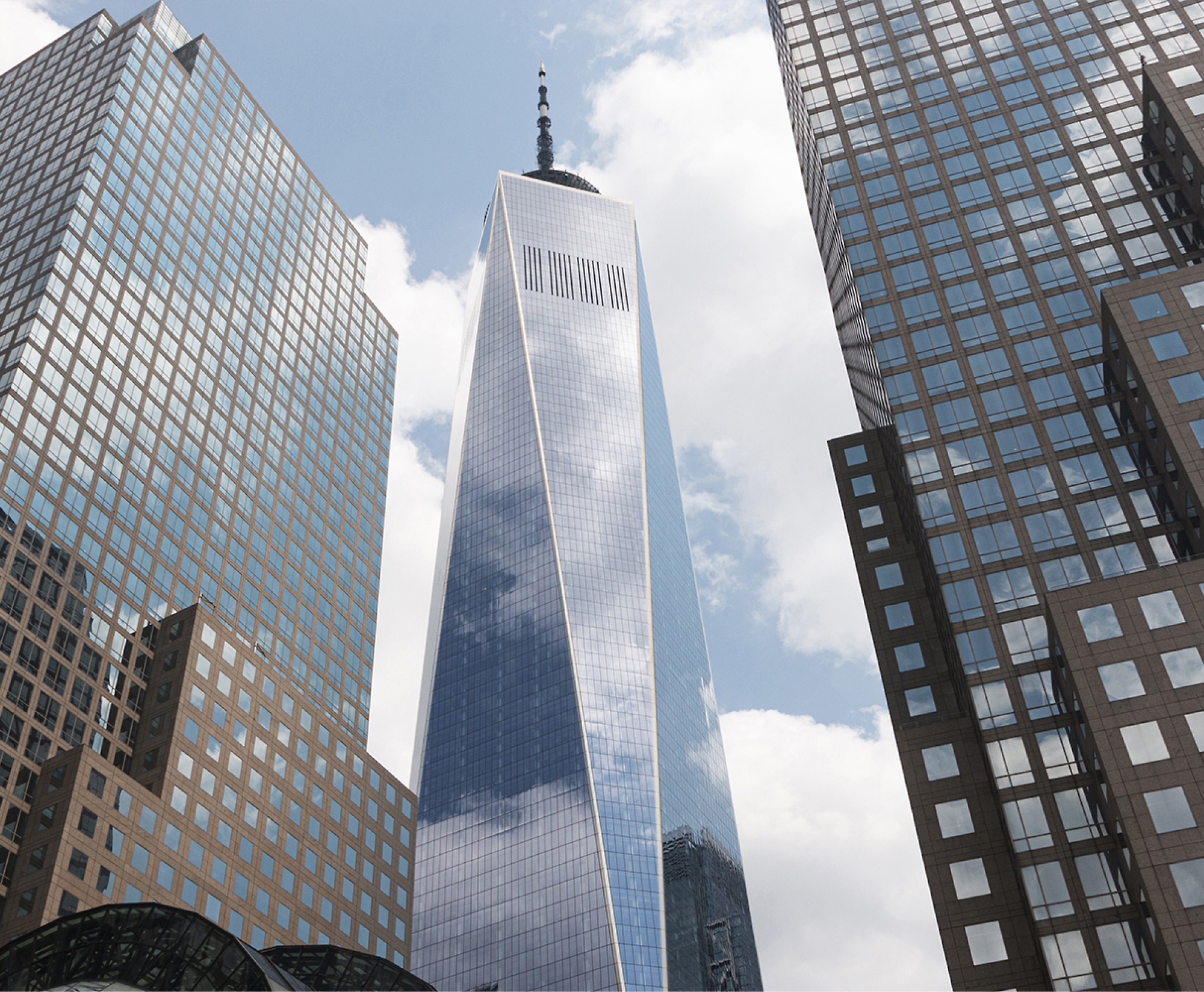 A tall, reflective skyscraper stands between two other high-rise buildings under a partly cloudy sky.