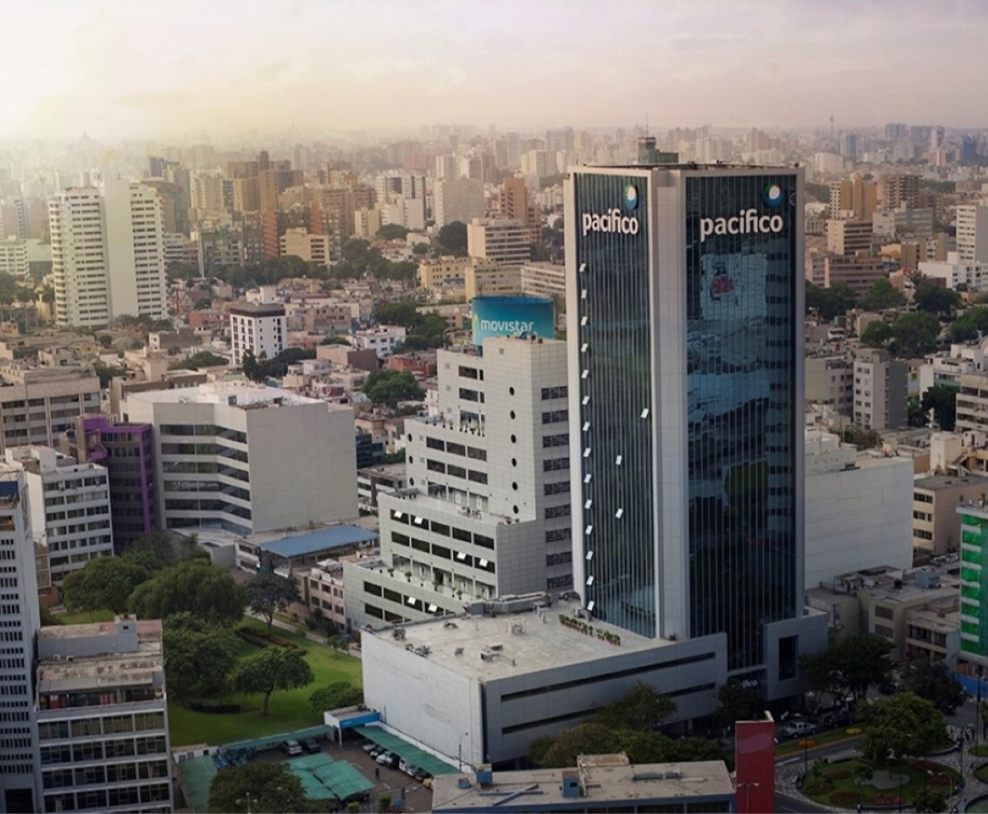 Aerial view of a cityscape featuring two prominent high-rise buildings labeled "pacifico" surrounded by smaller buildings, green spaces.