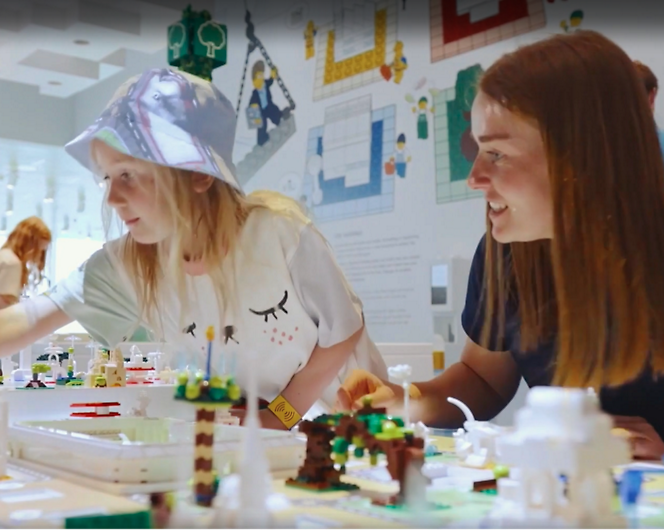 Two children at the LEGO House explore and build with LEGO bricks on a white table