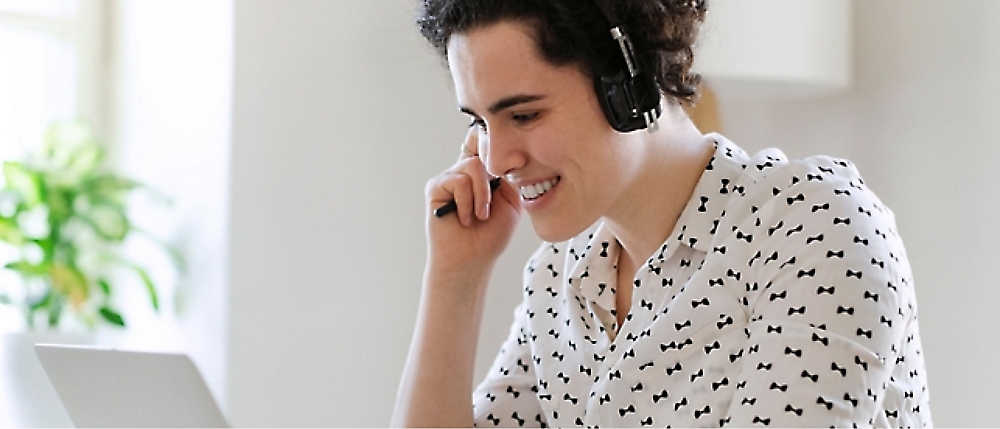 Person with curly hair wearing headphones and a white shirt with black bowtie patterns