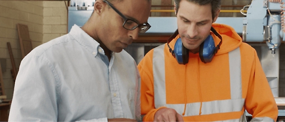 Two men examining documents in an industrial setting