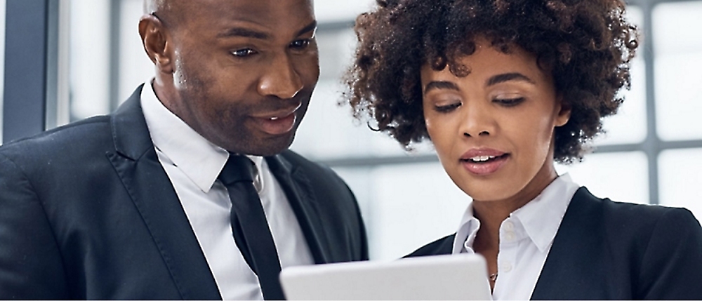 Two professionally dressed people are looking at a document together.