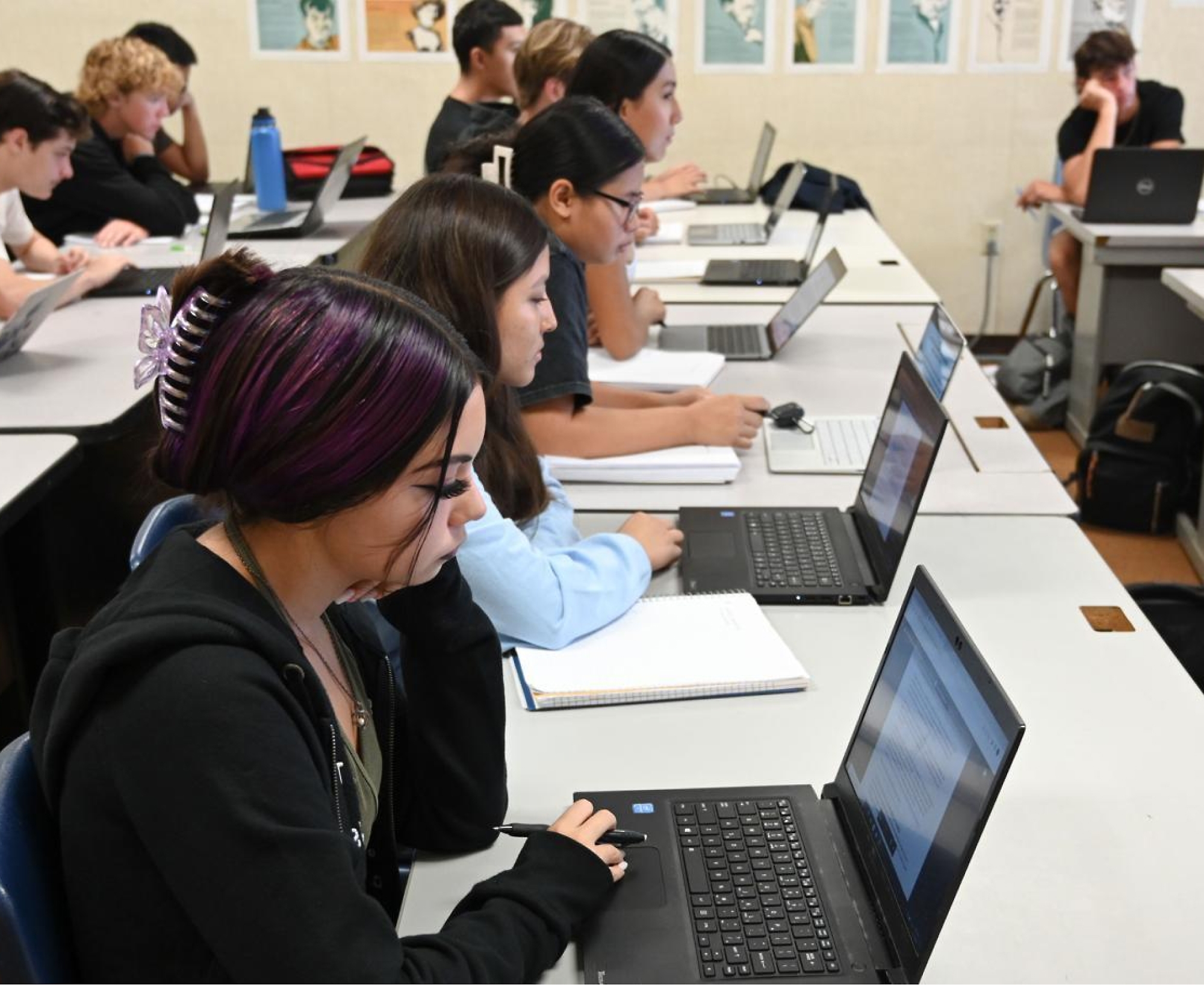 A group of people sitting at tables with laptops.