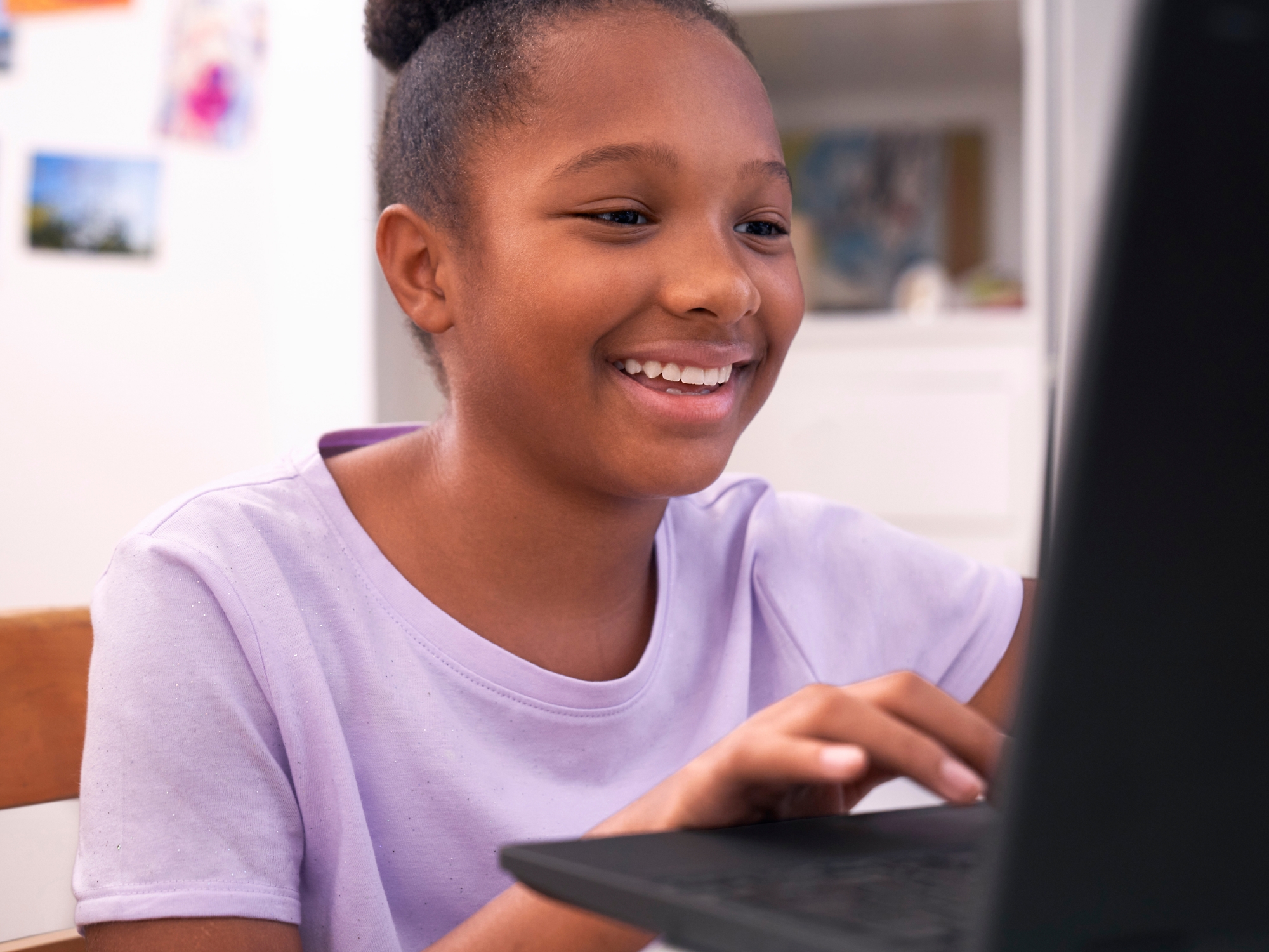 A young child smiling at a computer.