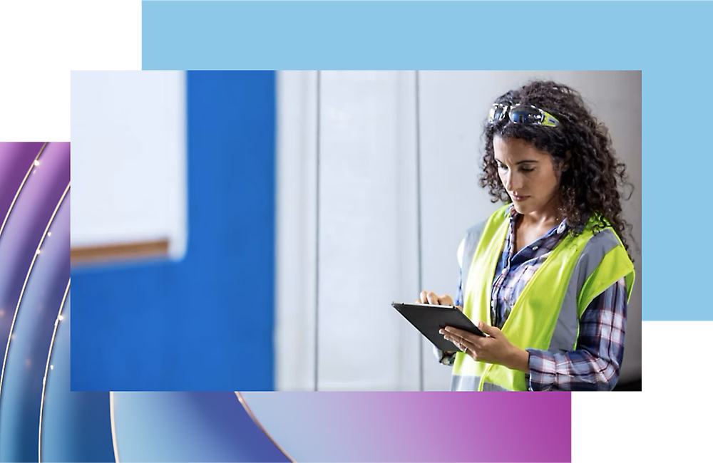 A person in a safety vest and safety glasses looking at a tablet